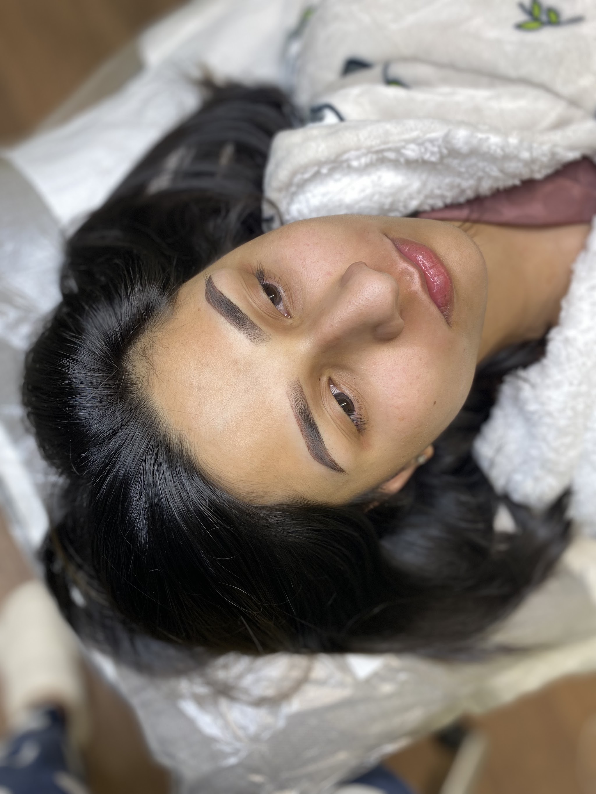 Client relaxing on the couch with freshly finished brows